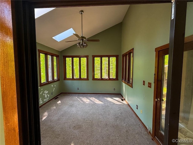 unfurnished room featuring ceiling fan, a skylight, carpet, baseboards, and high vaulted ceiling