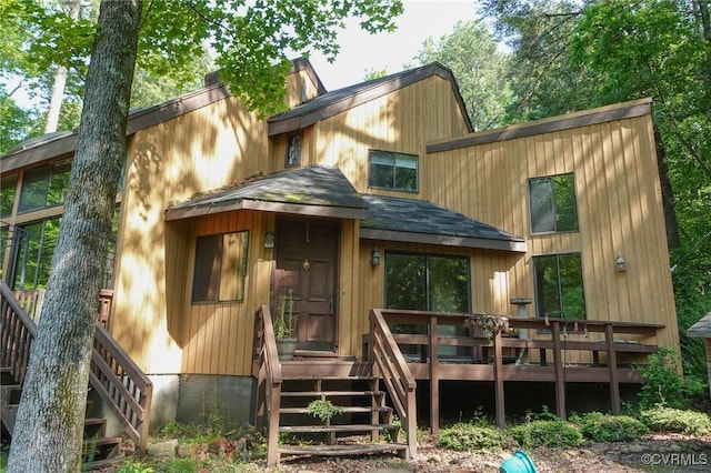 back of property with stairway, a wooden deck, and roof with shingles