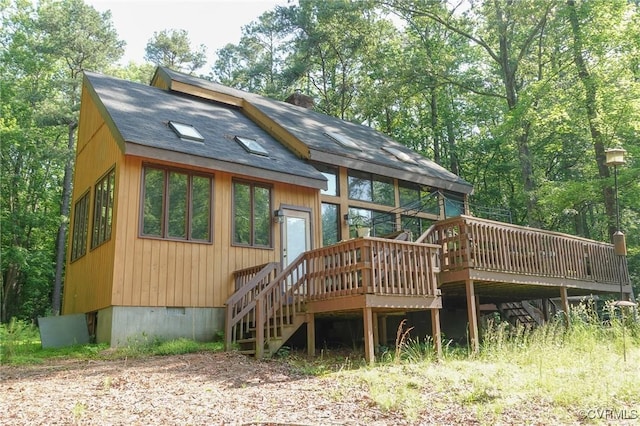 rear view of property with a wooden deck, stairs, and a shingled roof