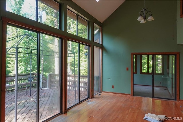 entryway featuring high vaulted ceiling, a chandelier, wood finished floors, and baseboards