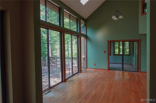 entryway with high vaulted ceiling, a chandelier, wood finished floors, and baseboards