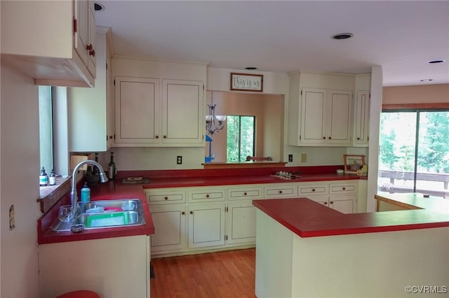 kitchen featuring a sink, light wood finished floors, dark countertops, and white cabinetry