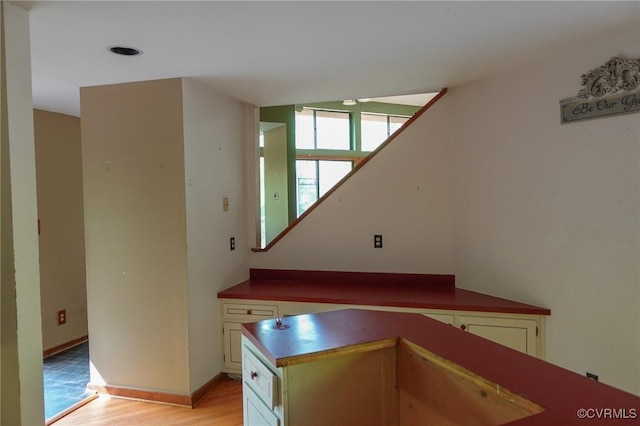 kitchen with light wood-style flooring, baseboards, and white cabinets