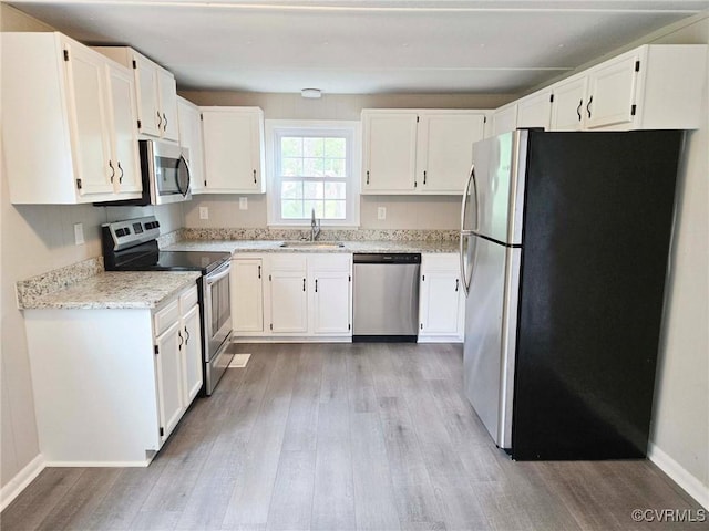 11400 Weyanoke Rd, Charles City, VA 23030 - kitchen featuring appliances with stainless steel finishes, light wood finished floors, light stone countertops, and white cabinetry
