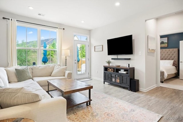 living room with wood finished floors, baseboards, and recessed lighting