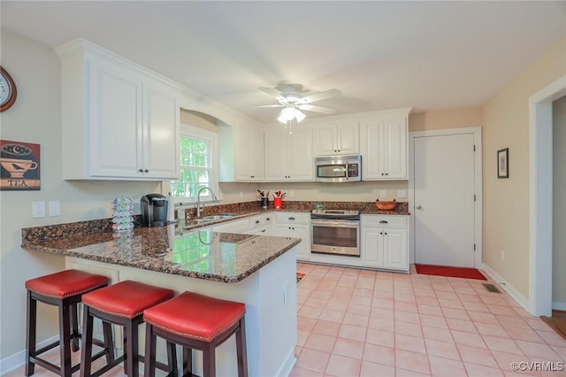 4606 Oak Hollow Rd, Chester, VA 23831 - kitchen featuring stainless steel appliances, a peninsula, white cabinets, dark stone countertops, and ceiling fan