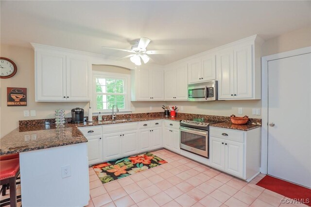 4606 Oak Hollow Rd, Chester, VA 23831 - kitchen with stainless steel appliances, a peninsula, white cabinets, dark stone counters, and ceiling fan