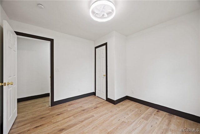 unfurnished bedroom featuring light wood-style flooring, baseboards, and a chandelier