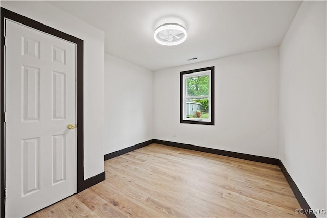 spare room featuring baseboards and light wood finished floors