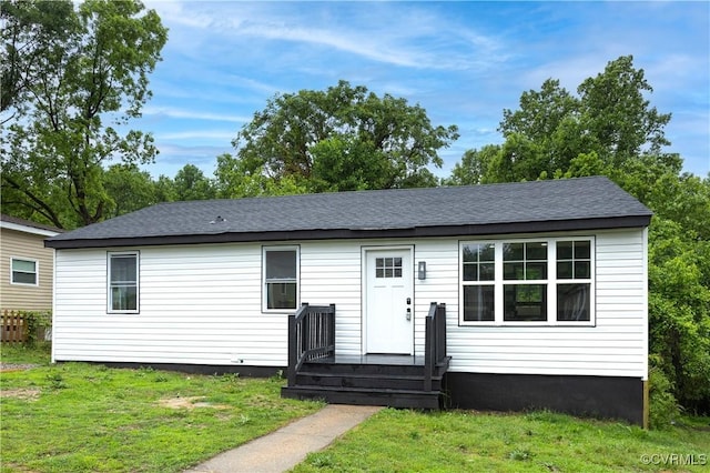 view of front of home with a front yard and roof with shingles