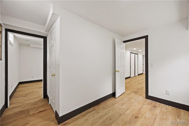 hallway featuring baseboards, light wood-type flooring, and recessed lighting