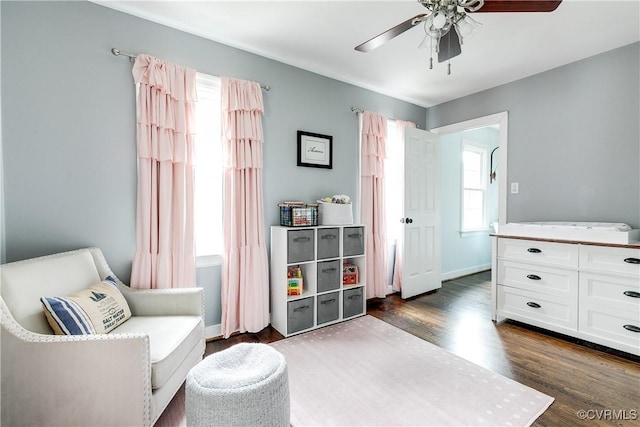 living area with a ceiling fan, dark wood-type flooring, and baseboards