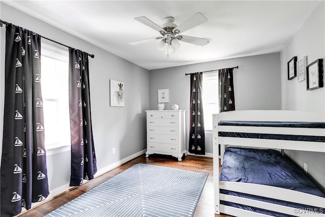 bedroom with multiple windows, wood finished floors, and baseboards
