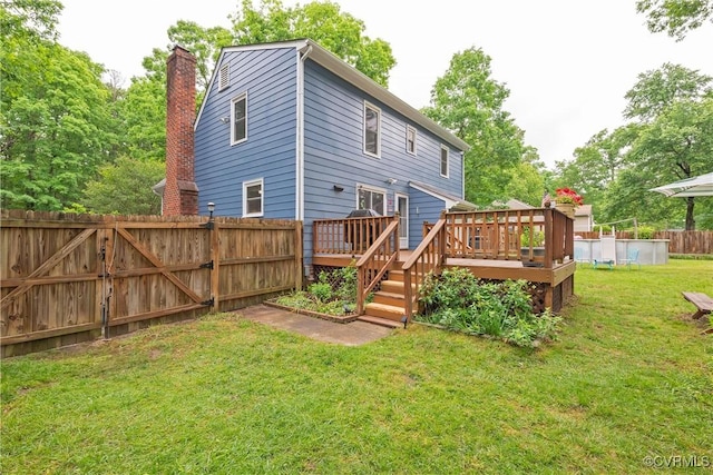 rear view of property featuring a deck, an outdoor pool, a chimney, and a gate