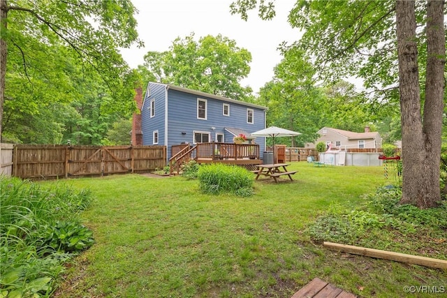back of house featuring a wooden deck and a swimming pool