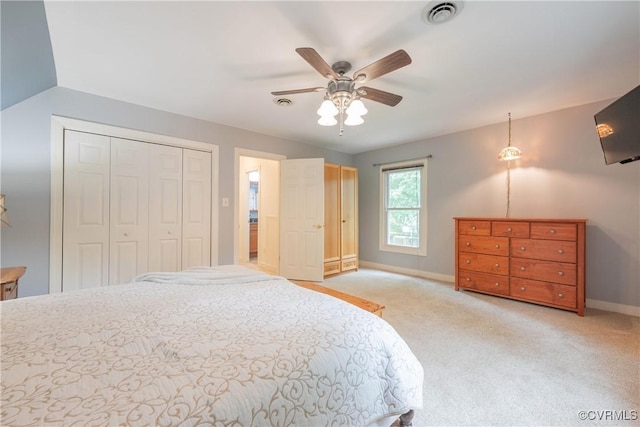 bedroom with baseboards, light colored carpet, a closet, and a ceiling fan