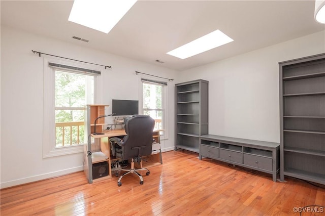 home office featuring a skylight, wood finished floors, and baseboards