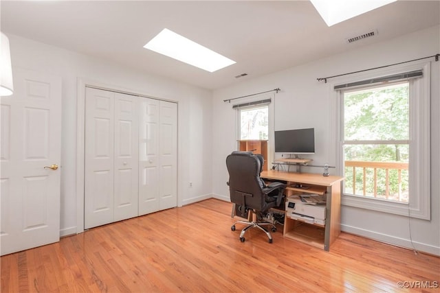 office space featuring a skylight, light wood-style flooring, and plenty of natural light