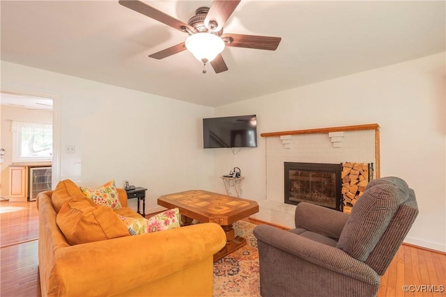 living room with a glass covered fireplace, hardwood / wood-style flooring, ceiling fan, wine cooler, and baseboards