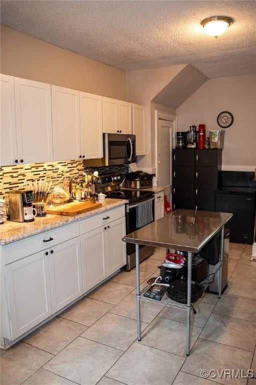 1024 W S Blvd, Petersburg, VA 23805 - kitchen with range with electric stovetop, stainless steel microwave, white cabinetry, a textured ceiling, and backsplash