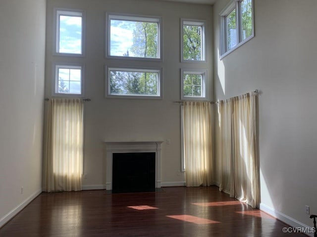 1919 Hounslow Ln, Manakin Sabot, VA 23103 - unfurnished living room with a towering ceiling, plenty of natural light, a fireplace with flush hearth, wood finished floors, and baseboards