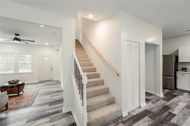 stairway with a ceiling fan, wood finished floors, recessed lighting, and baseboards