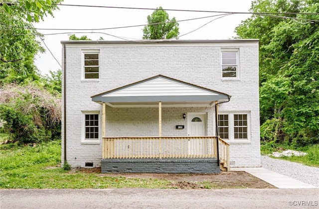 view of front facade with a porch, brick siding, and crawl space