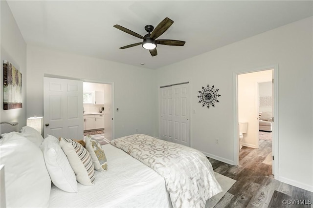 bedroom featuring wood finished floors, ensuite bath, a closet, a ceiling fan, and baseboards