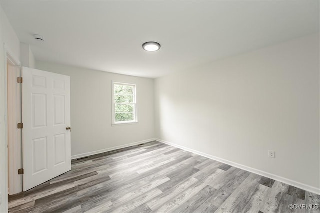 unfurnished room with wood finished floors, baseboards, and a smoke detector