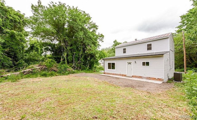 rear view of house featuring central AC, a lawn, metal roof, and a standing seam roof