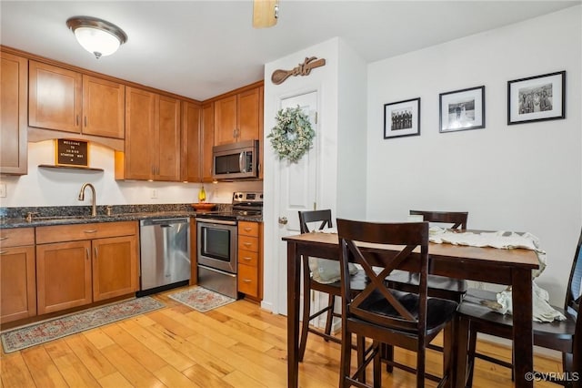 10808 Stanton Way, Henrico, VA 23238 - kitchen featuring stainless steel appliances, a sink, brown cabinets, light wood-style floors, and dark stone countertops