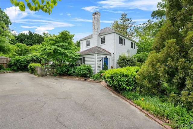 view of side of home with fence and a chimney