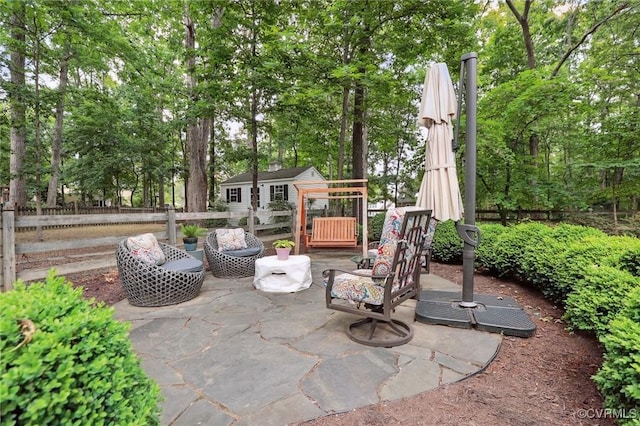 view of patio / terrace with fence, an outbuilding, and view of wooded area