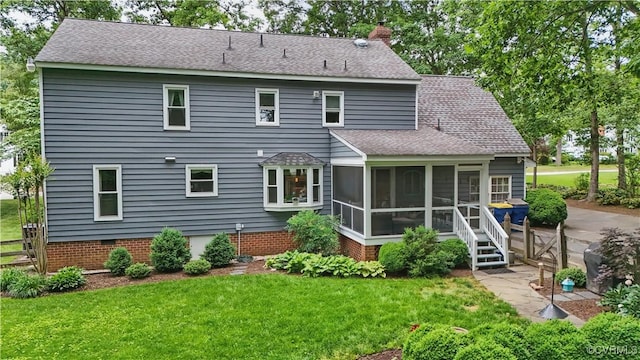 back of property with a sunroom, a yard, a chimney, and roof with shingles