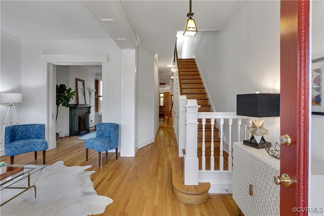stairs with wood finished floors, crown molding, and baseboards
