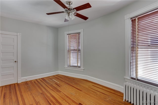 unfurnished room featuring radiator, baseboards, healthy amount of natural light, and wood finished floors