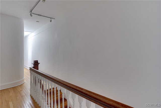 hall featuring light wood-style floors, an upstairs landing, and baseboards