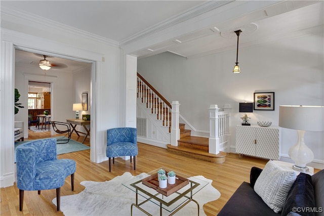 living room featuring crown molding, wood finished floors, and stairs