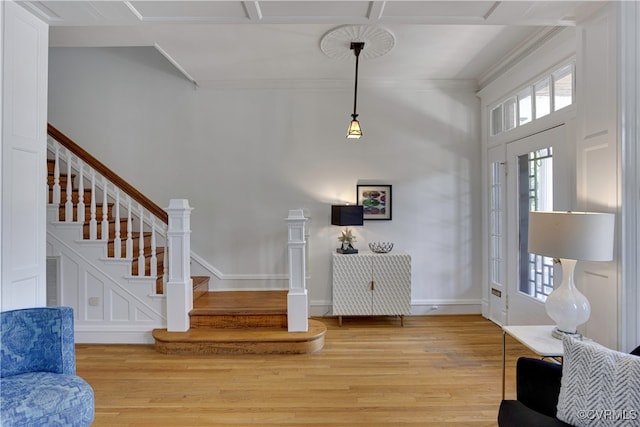 foyer entrance with light wood-style flooring, stairway, baseboards, and crown molding