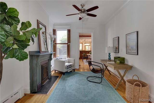 sitting room featuring a baseboard heating unit, crown molding, light wood-style floors, ceiling fan, and a fireplace with flush hearth