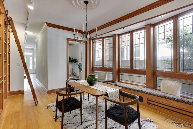 dining area featuring ornamental molding, light wood-style floors, baseboards, and a chandelier