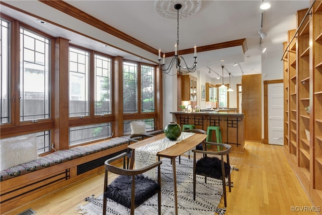 dining space with rail lighting, a chandelier, light wood-type flooring, and crown molding