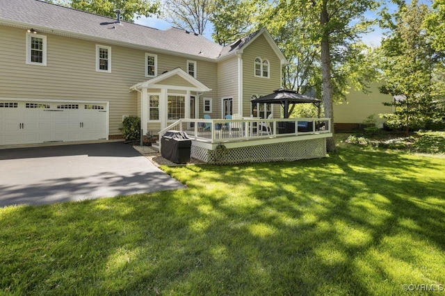 back of house featuring a gazebo, an attached garage, a wooden deck, and a lawn