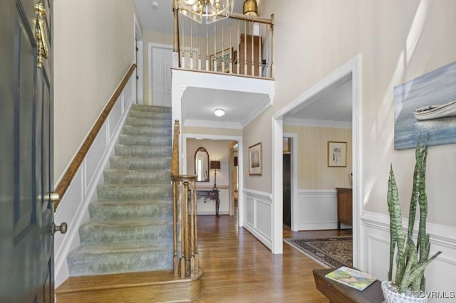 entrance foyer featuring a chandelier, wood finished floors, stairway, wainscoting, and ornamental molding