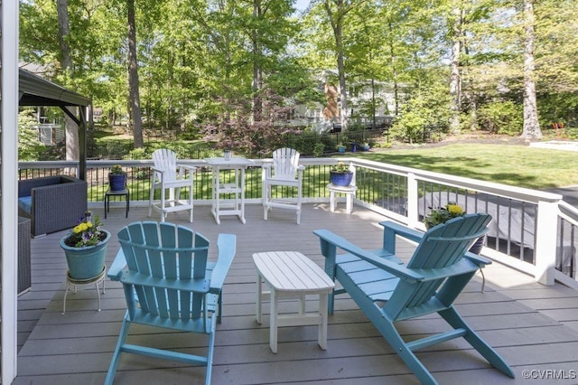 wooden terrace featuring a lawn and view of wooded area