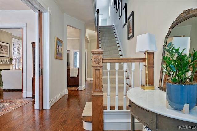 staircase with wood finished floors, ornamental molding, and baseboards