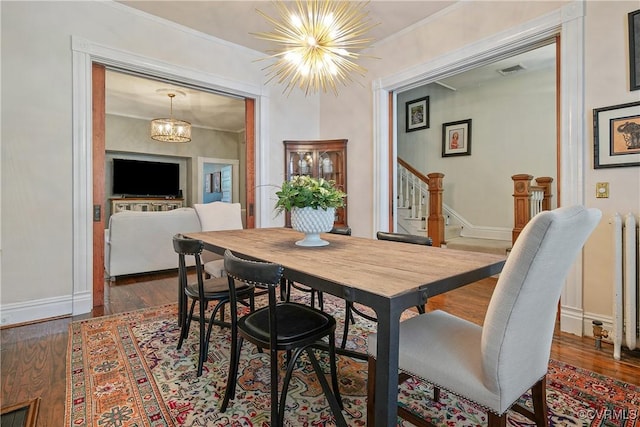 dining space featuring a chandelier, dark wood finished floors, stairway, baseboards, and ornamental molding