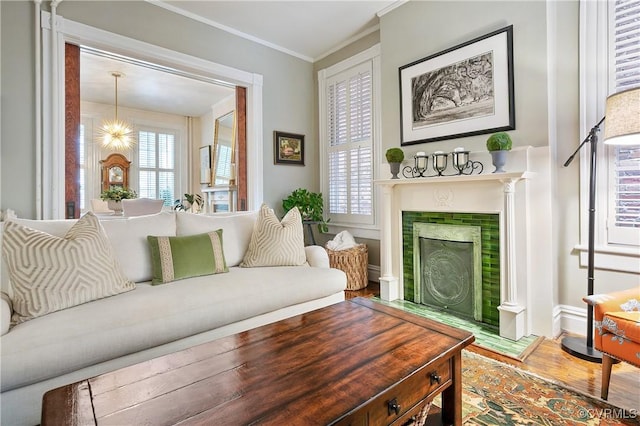 living area featuring wood finished floors, a fireplace, baseboards, and crown molding