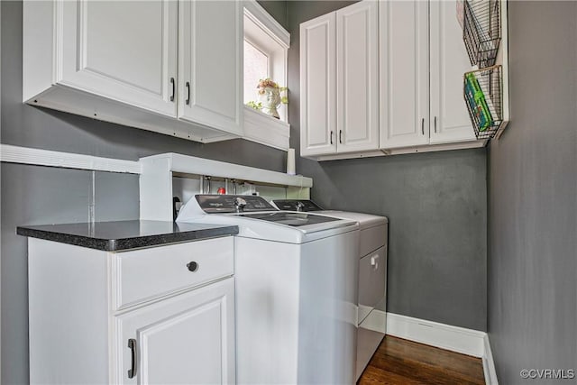 clothes washing area featuring washing machine and dryer, cabinet space, baseboards, and dark wood-style floors