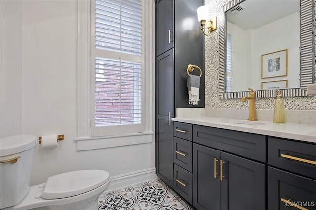 bathroom featuring toilet, vanity, tile patterned floors, and baseboards